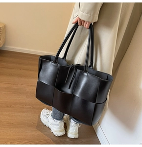 Close-up of wide-weave black leather tote bag showing intricate handcrafted texture
