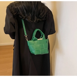 Dettaglio borsa intrecciata verde con tracolla in pelle e ganci in metallo dorato