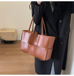 Detailed side view of caramel woven tote bag with large square weave on model
