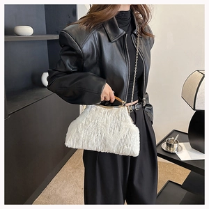 Detail of white faux fur evening clutch with gold metal frame and chain on a black coat