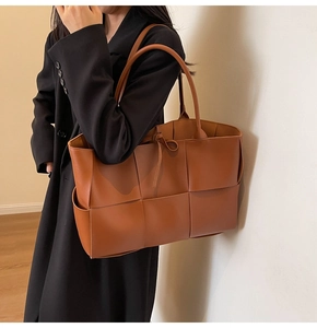 Detailed side view of brown woven tote bag featuring soft leather and knot drawstring detail
