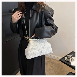 Detailed close-up of white plush evening bag with gold metal frame and chain strap