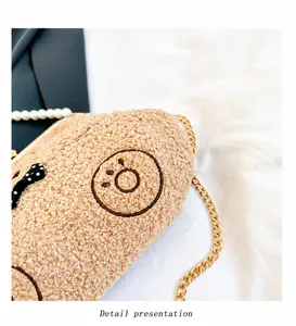 Detalle de bolso de peluche marrón con correa de perlas y cadena metálica dorada elegante