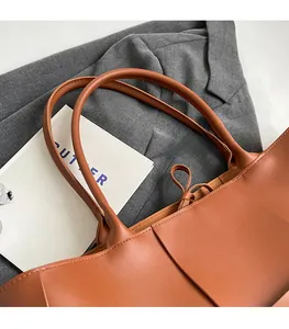 Detail of reinforced handles and drawstring tie on brown leather woven tote bag
