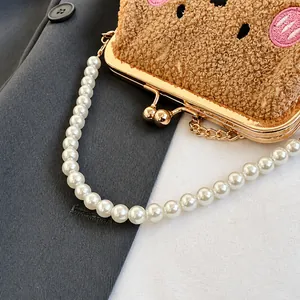 Detalle de bolso de felpa marrón con bordado animal y elegante asa de perlas finas