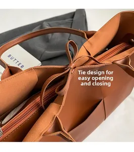 Detail of woven leather tote bag featuring tie closure and metallic smooth zipper