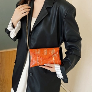 Bolso sobre naranja brillante con relieve de cocodrilo y cadena dorada en modelo