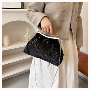 Chic black faux fur evening bag with sequins, gold frame, and wooden handle on a model