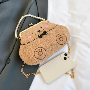 Detalle de bolso de osito de peluche marrón con asa de perlas y cadena oro