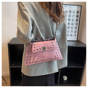 Pink studded crossbody bag with chain strap and vintage texture shown on grey blazer