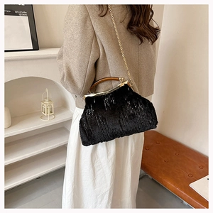 Detail of plush black evening bag with gold chain and wooden handle worn by a model