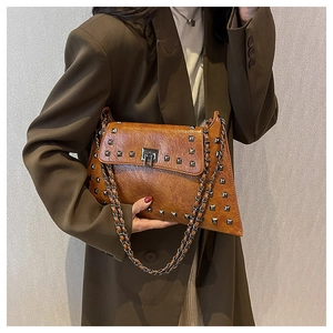 Detail of vintage brown leather handbag featuring silver square studs and chain strap
