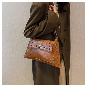 Detail of vintage brown studded shoulder bag with chain strap on a green blazer outfit