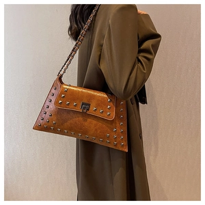 Brown vintage studded handbag with chain strap shown on model over shoulder
