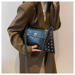 Detail of black studded shoulder bag with silver hardware and metallic chain strap