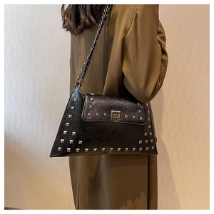 Detailed close-up of a black leather handbag with silver rivets and metal chain strap