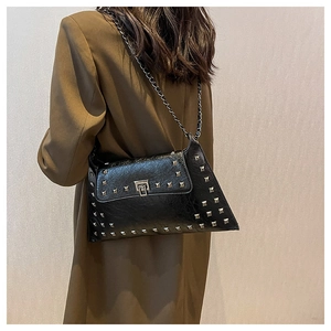 Detail of a black punk leather shoulder bag with silver studs and chain strap on a model