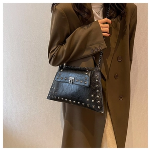 Model wearing a vintage black studded shoulder bag with glossy oil-waxed leather and chain