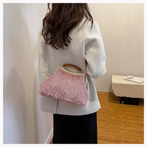 Pink faux fur evening bag with wooden handle and gold chain strap shown on a model