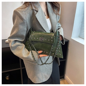 Close-up of dark green wrinkled leather bag with silver studs and chain strap detail