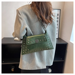 Detail of dark green studded shoulder bag featuring silver rivets and metallic chain strap