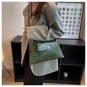 Detail of dark green leather shoulder bag with silver square rivets and chain strap