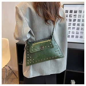 Detail of dark green vintage handbag with metallic rivets and chain strap on shoulder