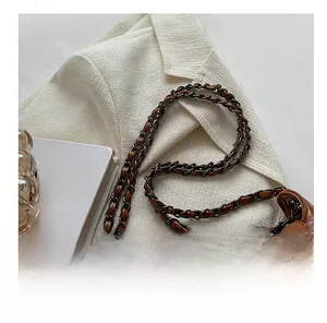 Detail of vintage brown leather handbag with metallic rivets and woven chain strap