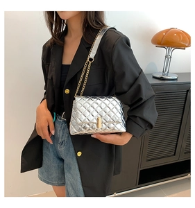 Detail of silver quilted chain bag with gold metal lock and metallic finish texture
