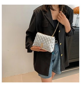 Close-up of a silver quilted chain shoulder bag with a gold twist lock on a black blazer