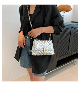 Detailed view of silver quilted chain bag with metallic finish and gold twist lock clasp