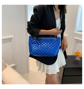 Close-up of metallic blue quilted tote bag with golden chain strap on a model
