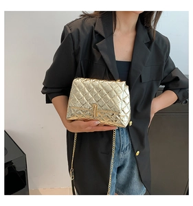 Close-up of golden quilted crossbody bag with metallic finish and chain strap on a model