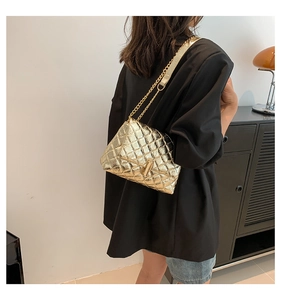 Close-up of golden quilted texture and metallic chain strap on a stylish crossbody bag
