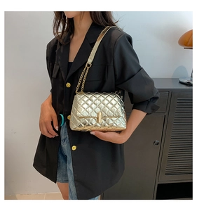 Detail of gold quilted crossbody bag featuring elegant chain strap and metal lock closure
