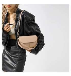 Elegante borsa a sella beige abbinata a una giacca di pelle nera per un look autunnale