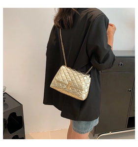 Close-up of golden quilted chain bag with metallic finish and luxury rectangle lock