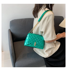 Detailed view of green quilted leather bag with gold chain strap worn over a beige blazer