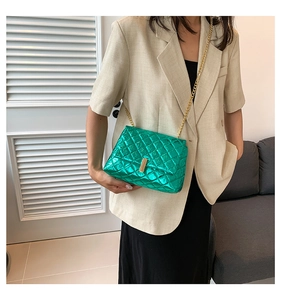 Detail of bright green quilted texture on chain bag with gold metal clasp and strap