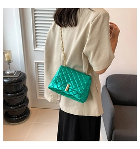Detail of metallic green quilted crossbody bag with gold chain strap and metal lock