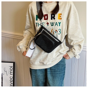 Close-up of black leather crossbody bag with silver studs and striped woven strap