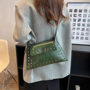 Dark green leather crossbody bag with silver studs and chain strap on a grey blazer