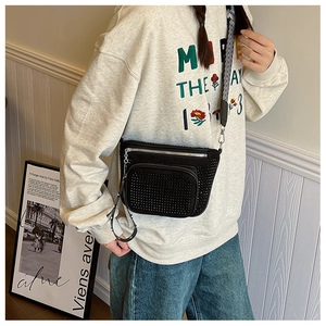 Detail of black rhinestone crossbody bag with wide striped strap and silver zippers