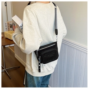 Crossbody bag with silver studs and geometric strap shown on a model's back