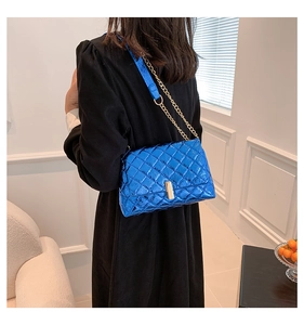 Close-up of quilted electric blue shoulder bag with golden chain and metallic finish