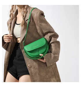 Dettaglio della borsa a sella verde brillante con logo bianco e texture in pelle liscia
