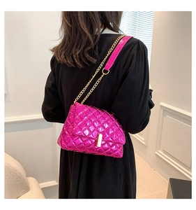 Close-up of magenta metallic quilted bag with golden chain strap on a black dress