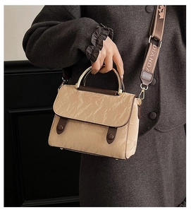 Detail of a khaki crossbody bag with pleated texture and stylish metal arch handle
