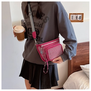 Detail of rose red crossbody bag with silver studs and a striped wide shoulder strap