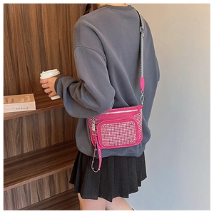 Detailed view of hot pink crossbody bag with silver rhinestones and striped strap